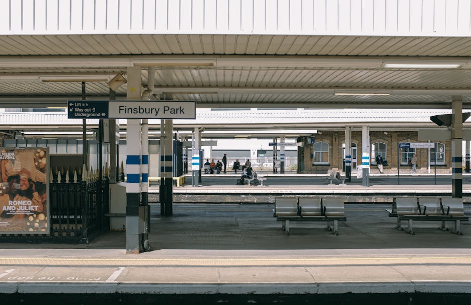 Finsbury Park train station platform with a sign displaying the station name in the upper center and a row of empty benches in the foreground. The platform has a clean, tiled surface with some marking