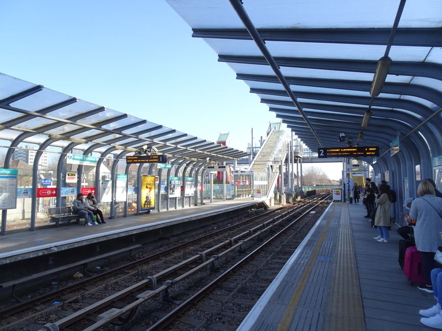 Finsbury Park train station platform with a sign displaying the station name in the upper center and a row of empty benches in the foreground. The platform has a clean, tiled surface with some marking